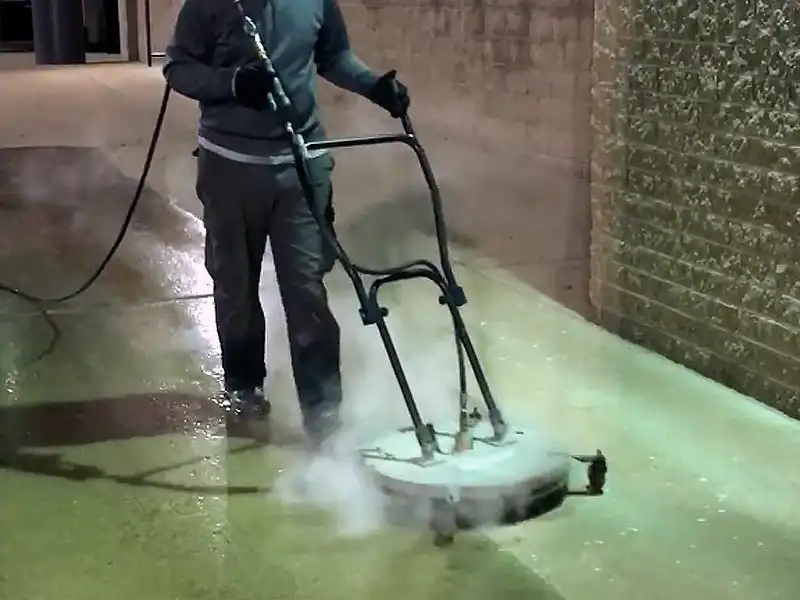 A HurriClean Pressure Washing technician performs after hours conrete surface cleaning service on a concrete sidewalk in front of Louisville area retail store.