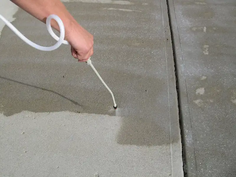 A commercial concrete sidewalk at a business property in Louisville being sprayed with sealer by a HurriClean Pressure Washing technician.