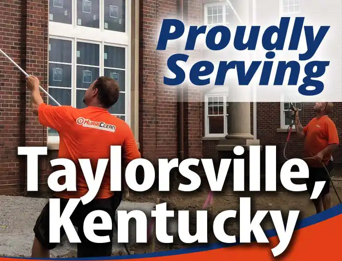 HurriClean Pressure Washing & Sealing techs wearing bright orange shirts soft wash a brick building with overlaid text that reads Proudly Serving Taylorsville, Kentucky.
