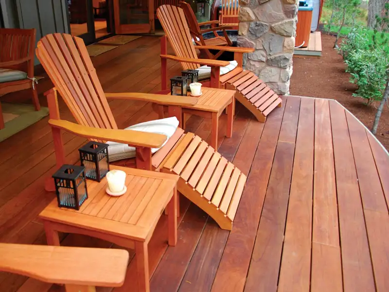 A wooden deck with adirondack chairs in the Crestwood KY area professionally cleaned, stained, and sealed in a redwood color.