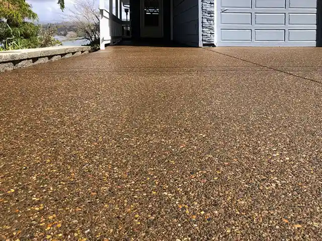 Detail view of a properly sealed exposed aggegrate driveway in front of a lake cottage home in the Louisville area.